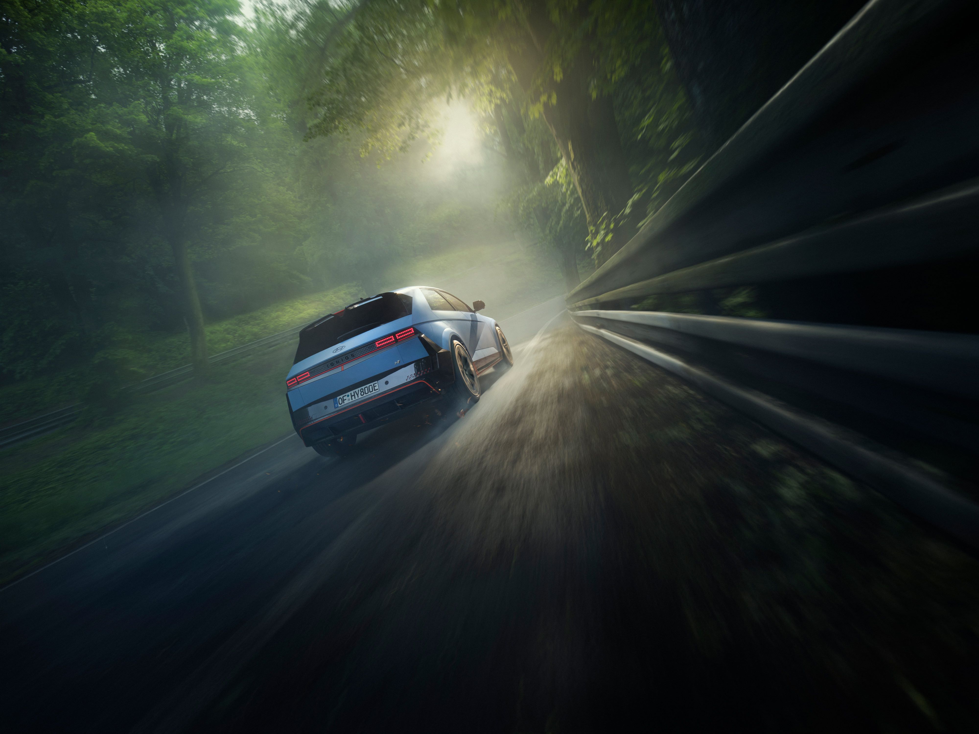 A Hyundai IONIQ 5 N high-performance EV seen from behind driving on a racetrack with trees.